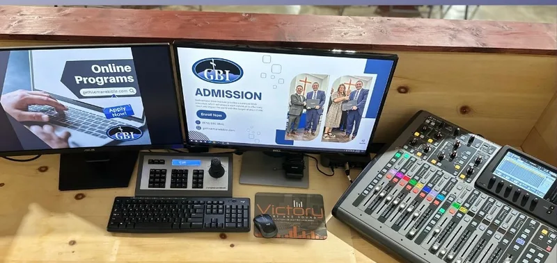 Gethsemane Bible Institute production position with two computer displays, camera controller, keyboard, and digital audio console