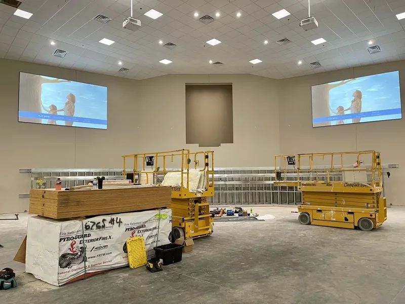 Dual projection screens operating above construction lifts in the unfinished Maple Springs auditorium